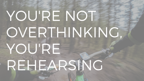 text "youre not overthinking you're rehearsing" over a racer on a mountain bike