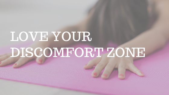 a woman stretching on a yoga mat with the text "love your discomfort zone"